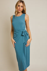 woman wearing a teal ribbed midi dress with a side bow detail and a fitted silhouette