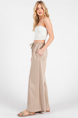 woman wearing a white ribbed crop top and beige wide-leg pants with an elastic waistband and side pockets