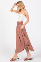 woman wearing a white crop top and a long dusty rose skirt with a smocked waist, walking sideways