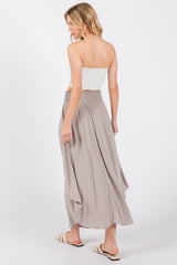woman wearing a light grey maxi skirt with a smocked waistband and a white spaghetti strap top, viewed from the back