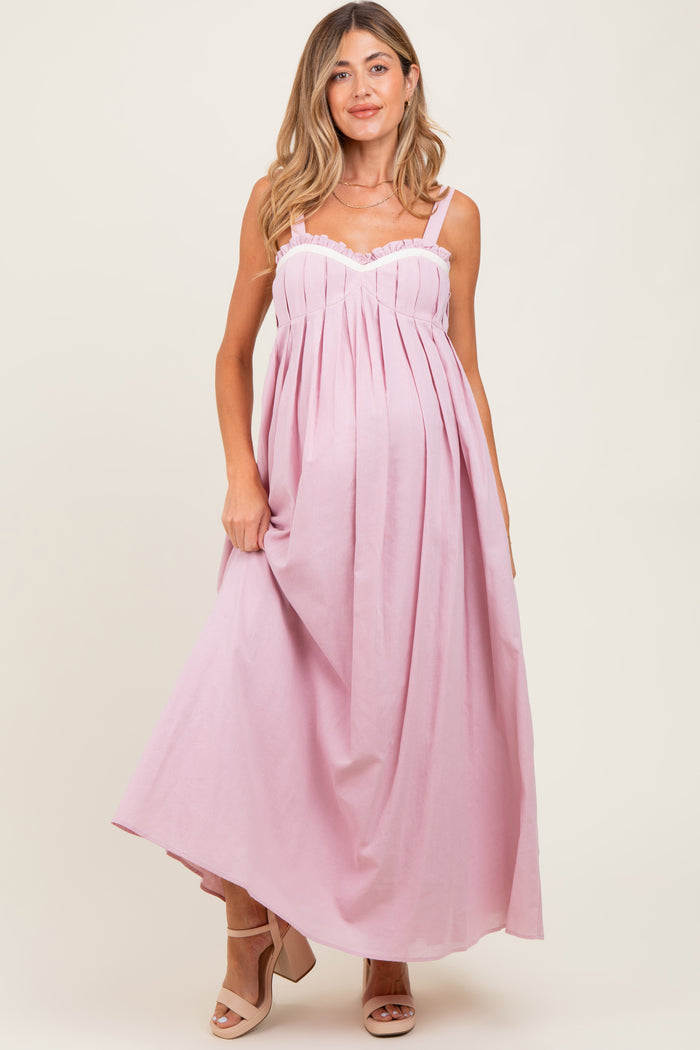 woman wearing a light pink maternity maxi dress with lace detailing and a visible baby bump