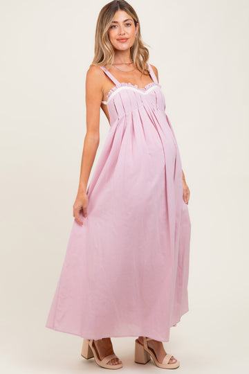 woman wearing a light pink maternity maxi dress with a fitted bodice and flowing skirt, showcasing her baby bump