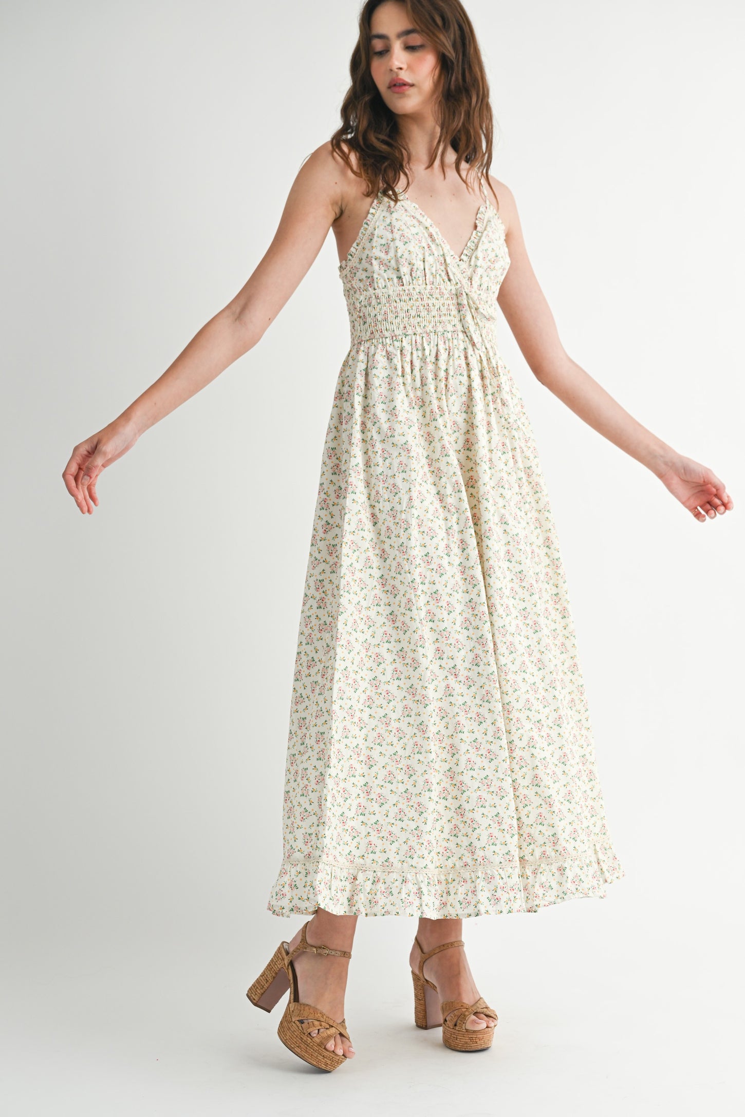 woman wearing a floral print maxi dress with thin straps and a smocked bodice, paired with platform sandals