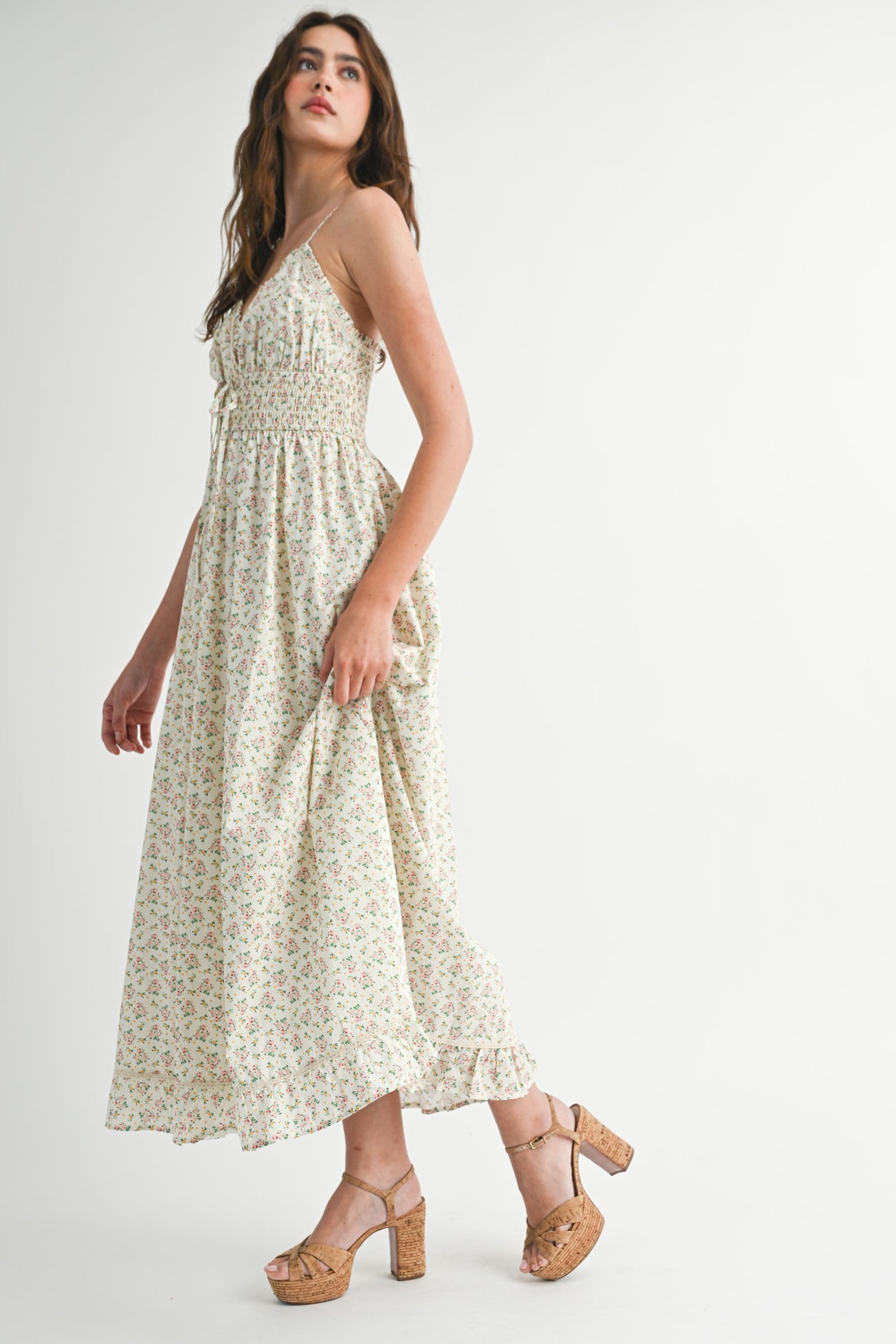 woman wearing a floral print maxi dress with adjustable straps and a smocked bodice, paired with tan block heel sandals