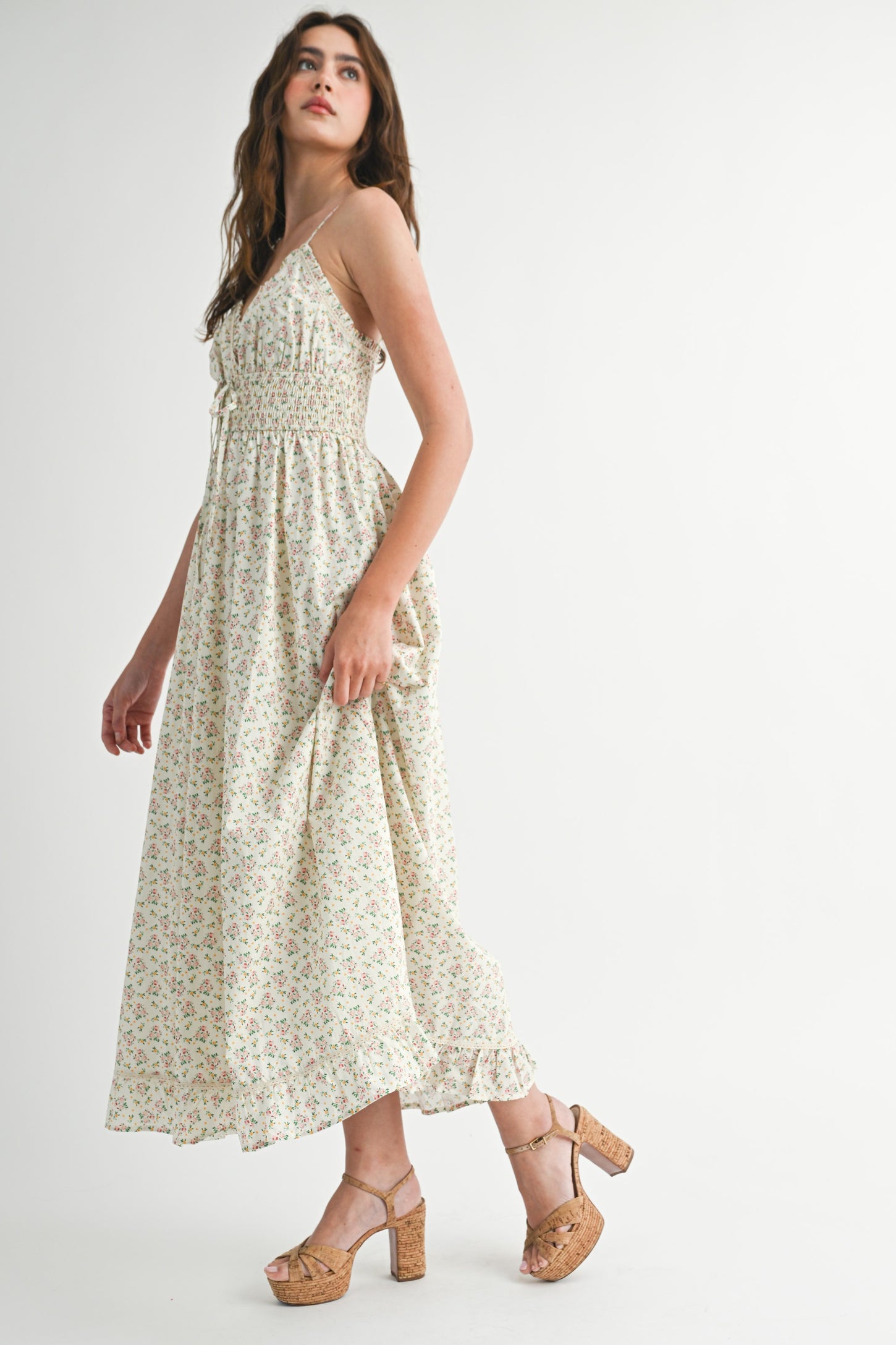 woman wearing a floral print maxi dress with adjustable straps and a smocked bodice, paired with tan block heel sandals