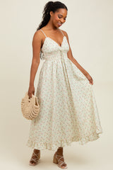 woman wearing a floral maxi dress with adjustable straps, holding a woven bag and standing against a light background