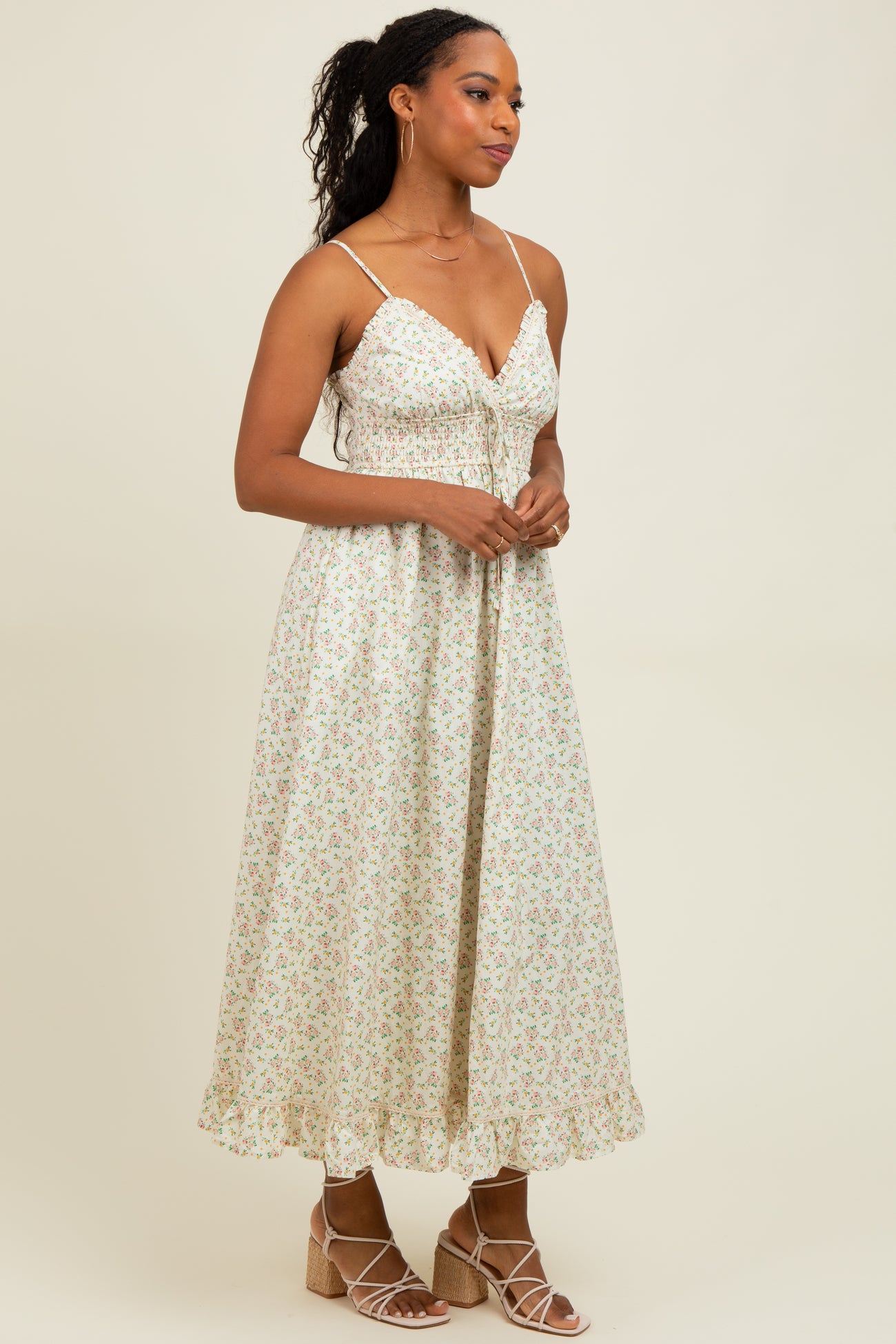 woman wearing a floral midi dress with spaghetti straps and ruffled hem, paired with strappy wedge sandals