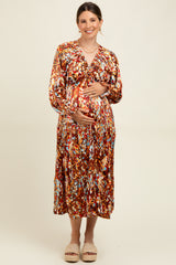 woman wearing a colorful floral maternity dress with long sleeves and a v-neck, showing her baby bump
