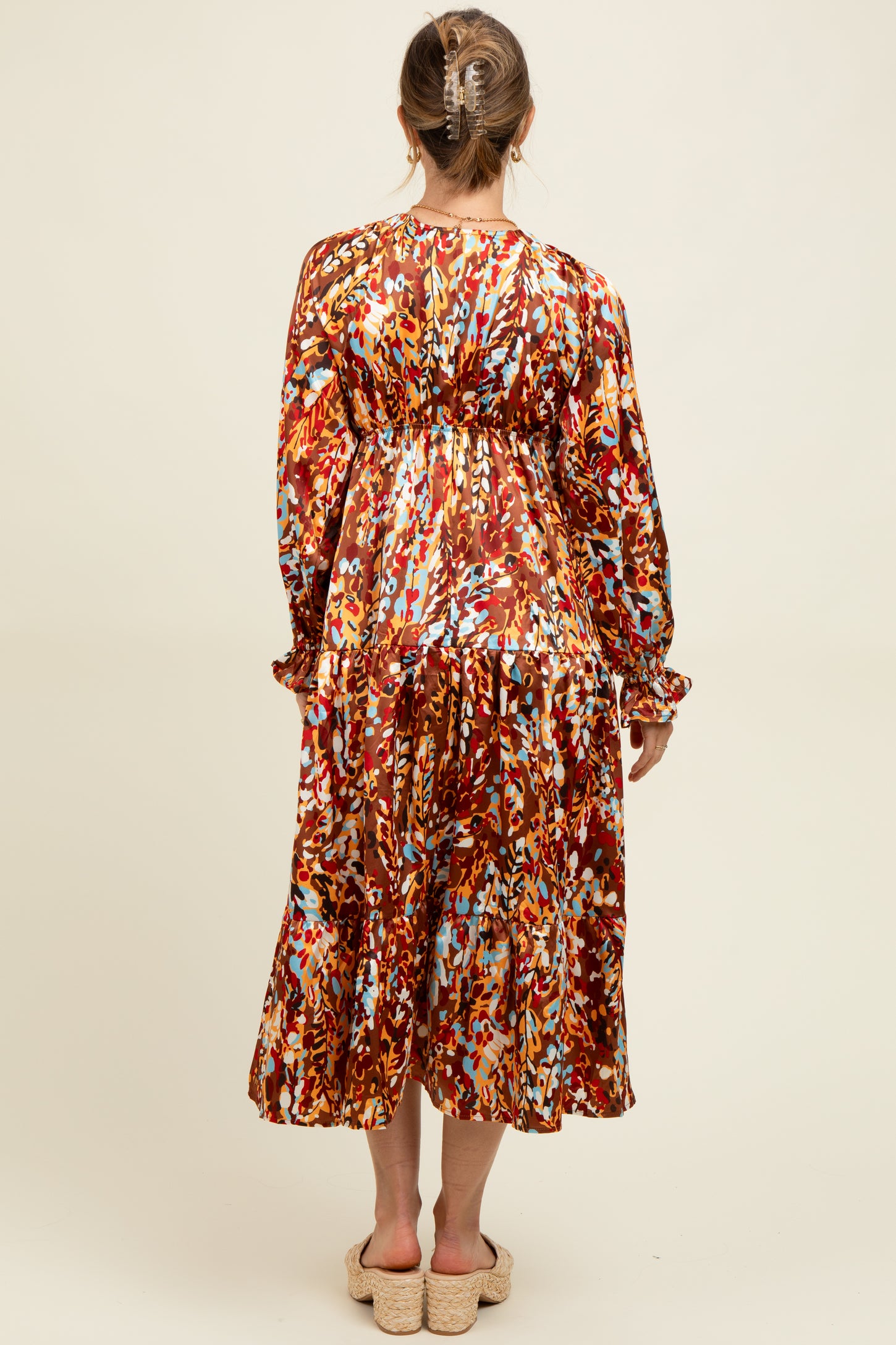 woman wearing a floral print maternity dress with a gathered waist and long sleeves, showing a baby bump from the back