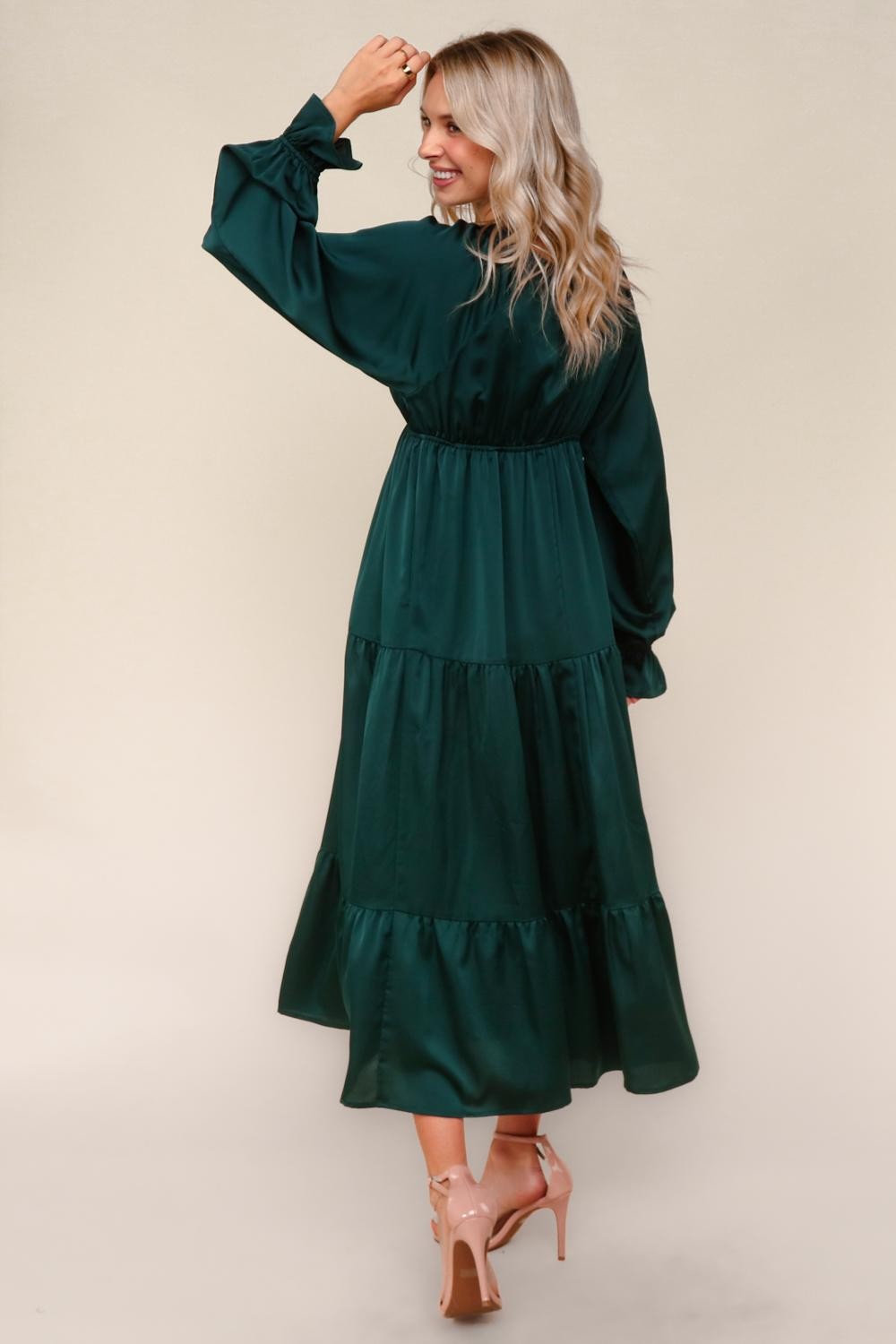 woman wearing a teal long sleeve tiered maxi dress, showing a back view with a cinched waist and ruffled hem