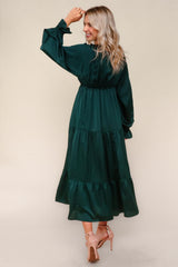 woman wearing a teal long sleeve tiered maxi dress, showing a back view with a cinched waist and ruffled hem