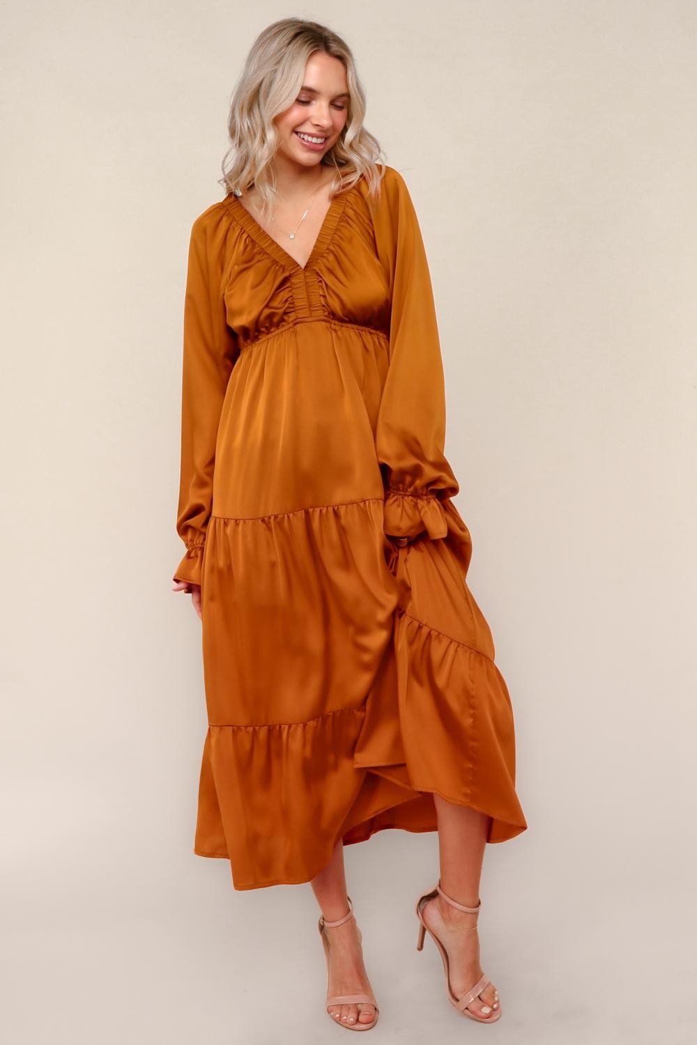 woman wearing a rust-colored long sleeve maxi dress with tiered ruffles and a deep v-neckline