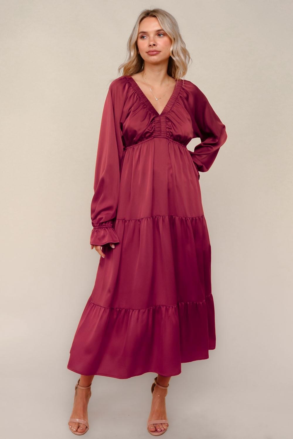 woman wearing a burgundy long sleeve tiered maxi dress with a v-neckline and ruffle details