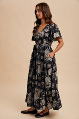 woman wearing a navy blue floral maxi dress with a v-neckline, ruffled sleeves, and pockets
