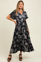 woman wearing a black floral maternity dress with flutter sleeves and a tie waist, showcasing a baby bump