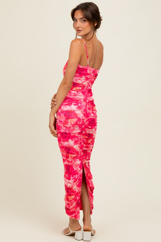 woman wearing a pink floral midi dress with ruching details and a high slit in the back