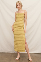 woman wearing a yellow ribbed maxi dress with textured stripes and a side slit, standing against a neutral backdrop