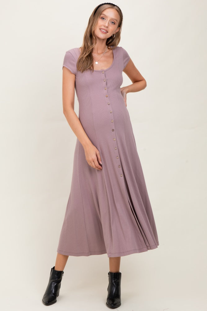 woman wearing a mauve short sleeve maternity dress with button details and a flowy skirt, showing off her baby bump