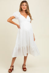 woman wearing a white maternity dress with puff sleeves and a ruffled hem, showing a baby bump