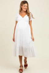 woman wearing a white maternity dress with puff sleeves and a tiered skirt, showing a baby bump