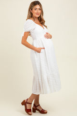 woman wearing a white short sleeve maternity dress with a tiered skirt and pockets, showing her baby bump