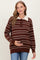 woman wearing a brown and cream striped maternity sweater with a collared neckline and holding her baby bump