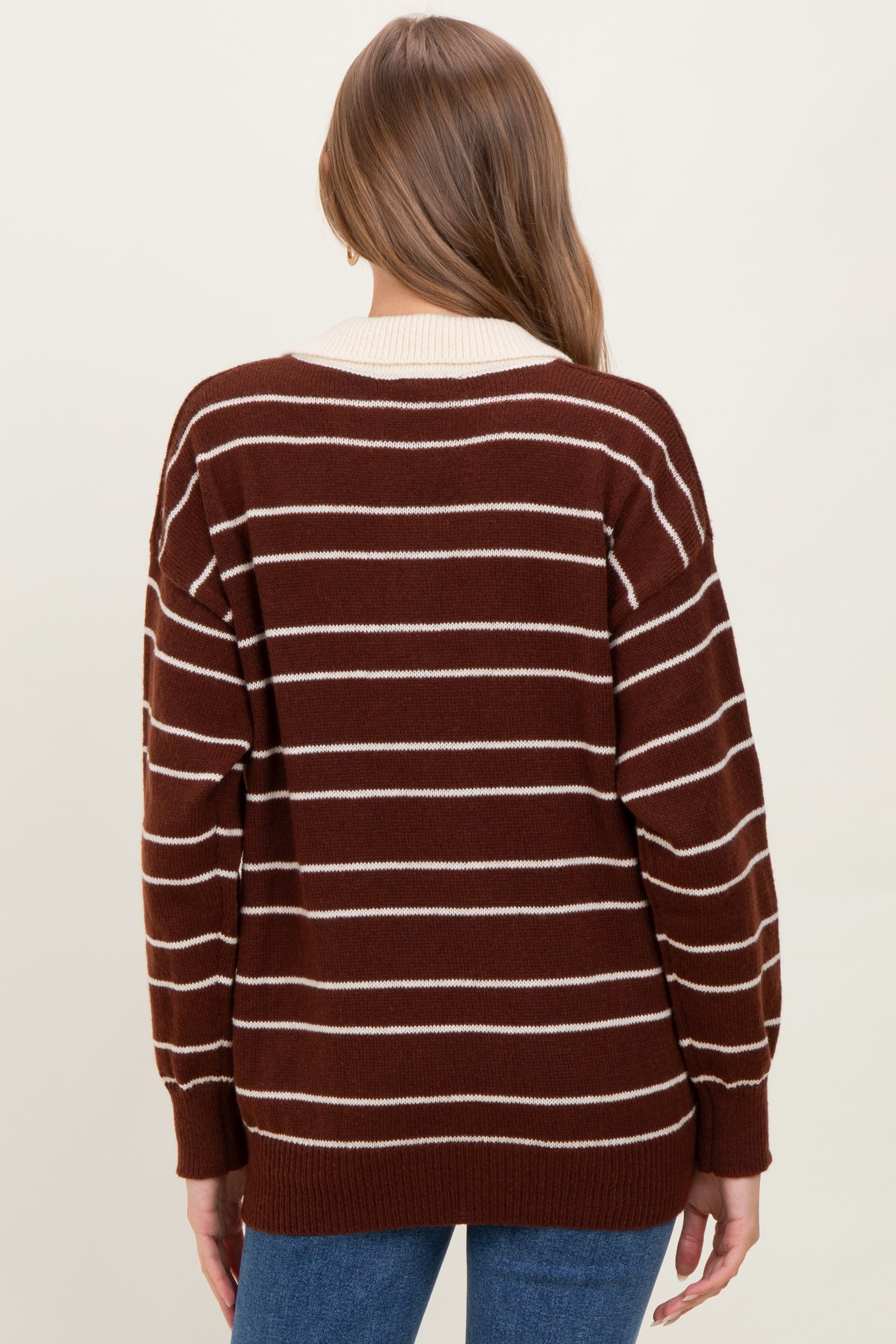 woman wearing a brown and white striped maternity sweater, showing the back view with a loose fit and ribbed cuffs