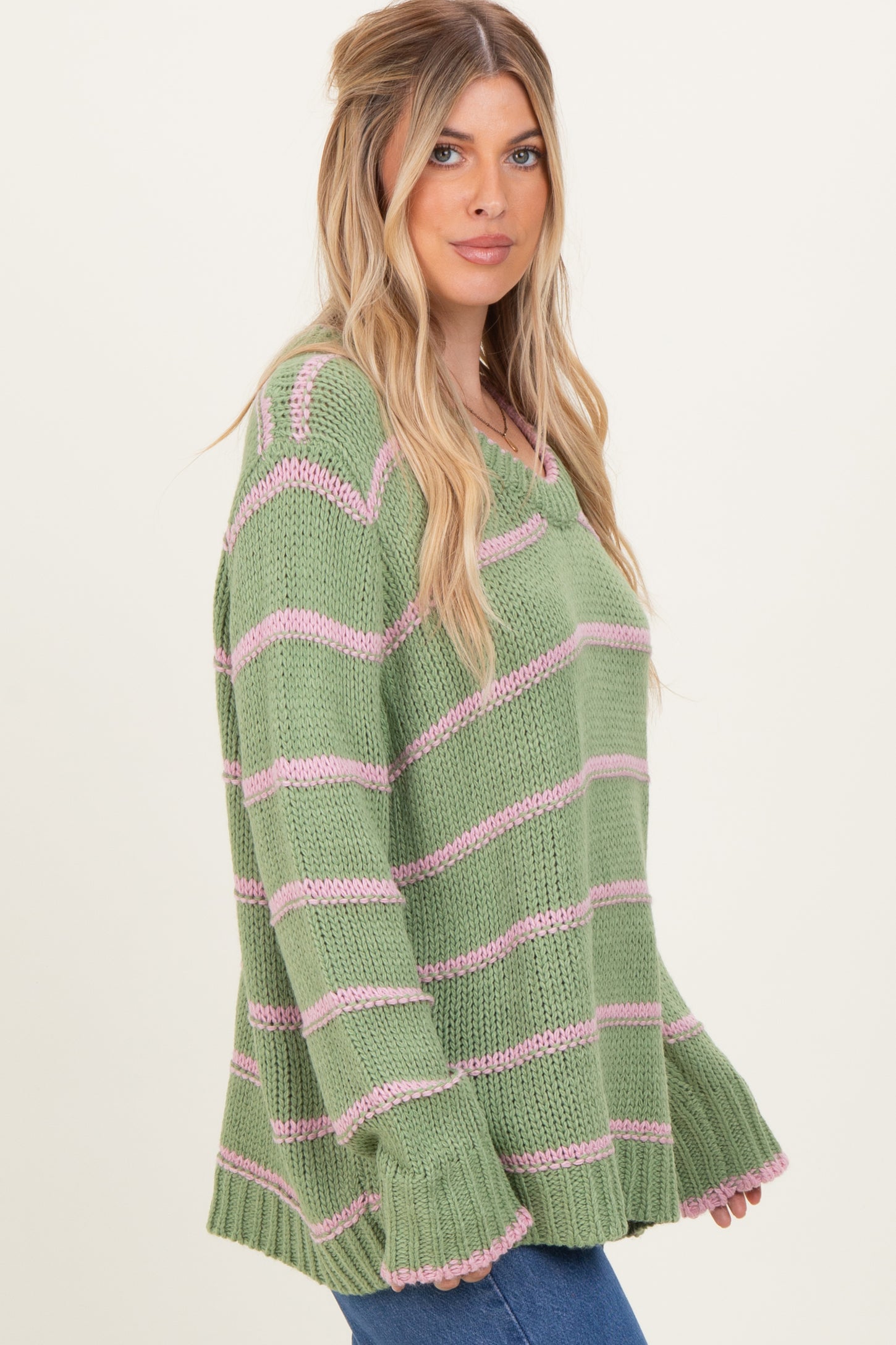 woman wearing a green and pink striped oversized sweater with bell sleeves and a relaxed fit