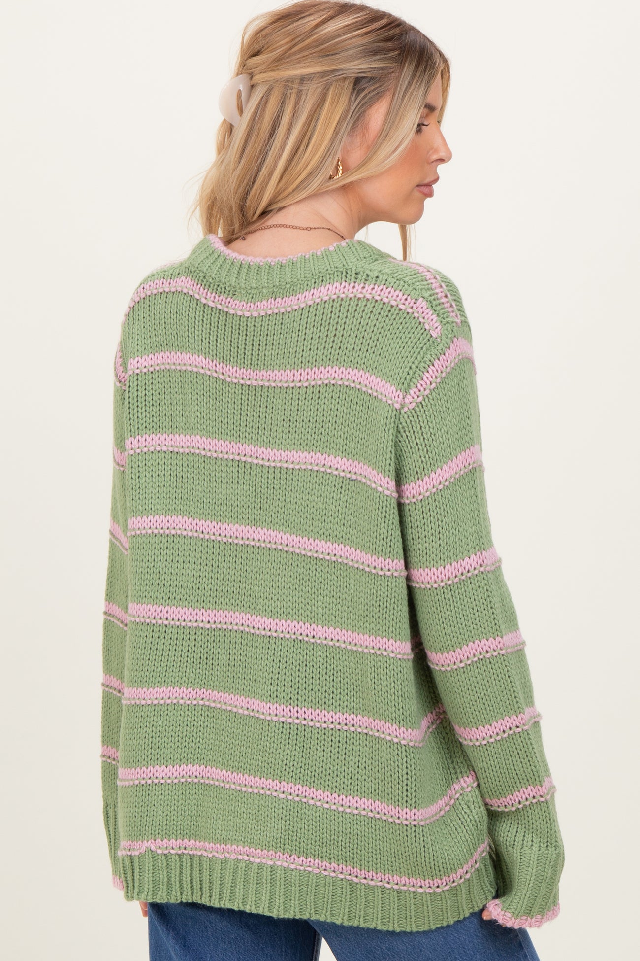 woman wearing a green and pink striped oversized sweater, view from the back