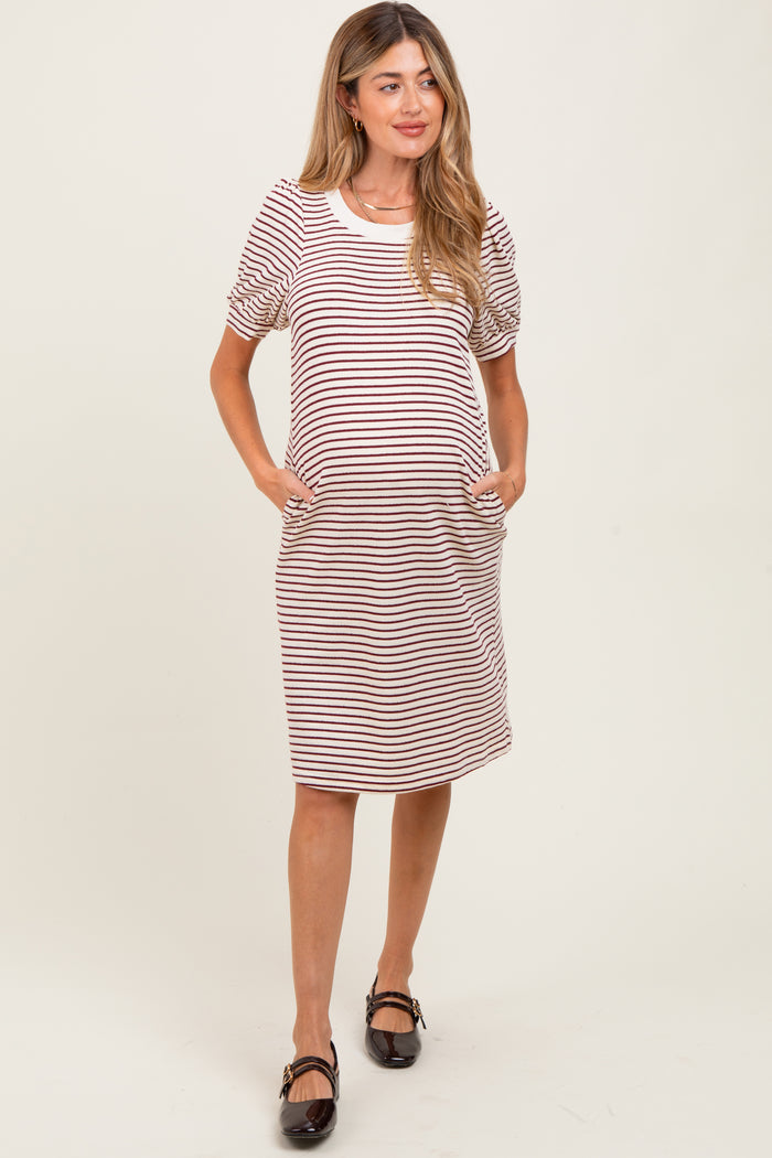 woman wearing a striped maternity dress with short puff sleeves and pockets, showcasing her baby bump