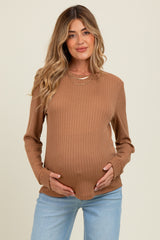 woman wearing a tan ribbed maternity top and holding her baby bump