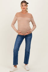 woman wearing a striped tan maternity sweater and jeans, holding her baby bump