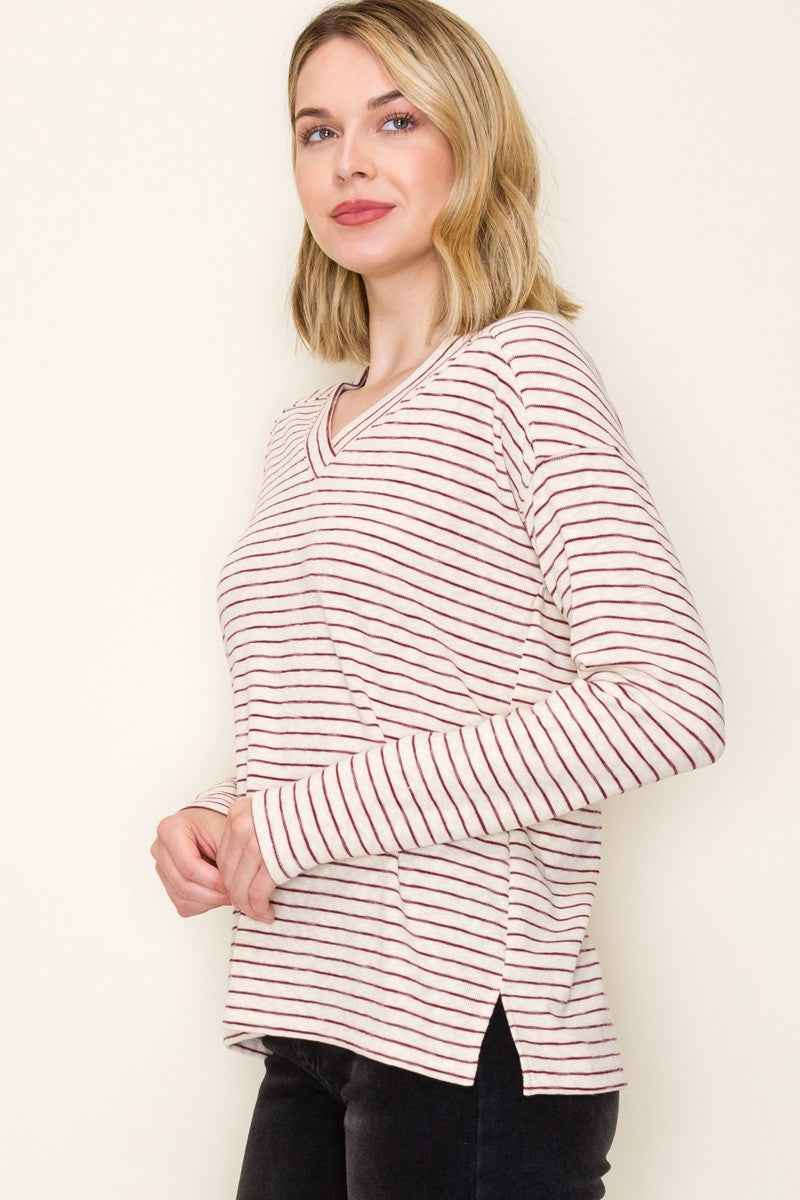 woman wearing a cream and burgundy striped long sleeve top with a v-neck and side slits