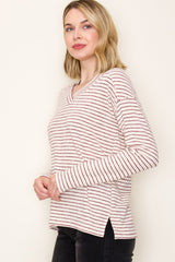 woman wearing a cream and burgundy striped long sleeve top with a v-neck and side slits