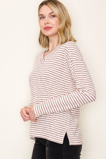 woman wearing a cream and burgundy striped long sleeve top with a v-neck and side slits