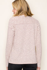 woman wearing a cream and burgundy striped long sleeve top, view from the back