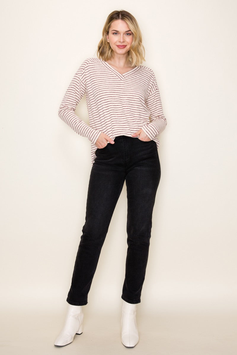 woman wearing a pink and white striped hooded long sleeve top with black skinny jeans and white ankle boots