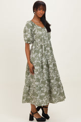 woman wearing a green floral print midi dress with puff sleeves and a tiered skirt, standing against a plain background
