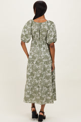 woman wearing a back view of a green floral print midi dress with puff sleeves and a cinched waist