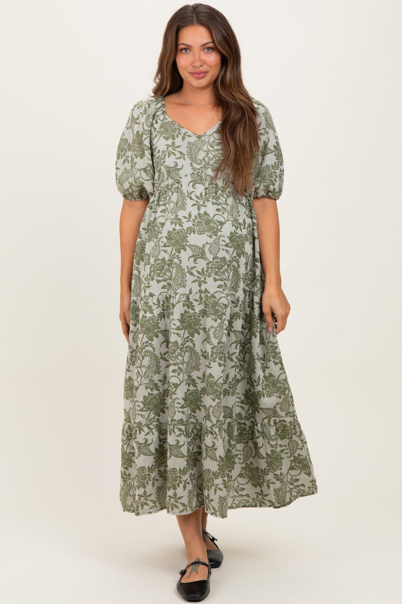 woman wearing a green floral print maternity maxi dress with puff sleeves and a v-neckline