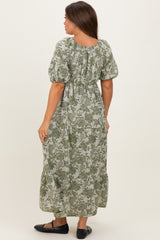 woman wearing a green floral print maternity maxi dress with puff sleeves and a tiered skirt, showing her baby bump