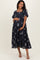 woman wearing a navy blue maternity dress with floral embroidery and short sleeves, holding her baby bump