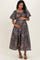 woman wearing a dark floral maternity maxi dress, holding her baby bump while standing gracefully