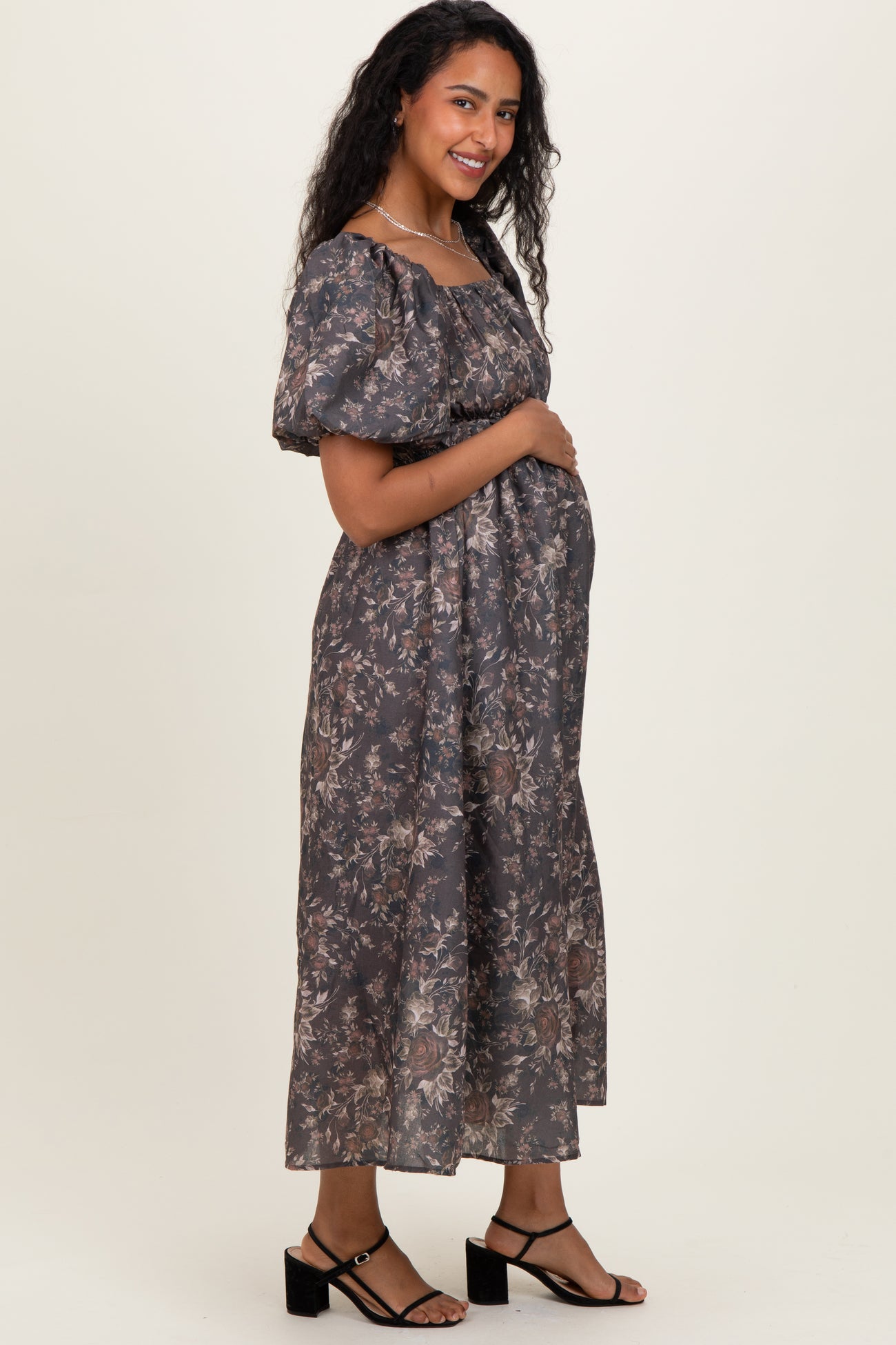 woman wearing a floral print gray maternity dress with puff sleeves and a visible baby bump