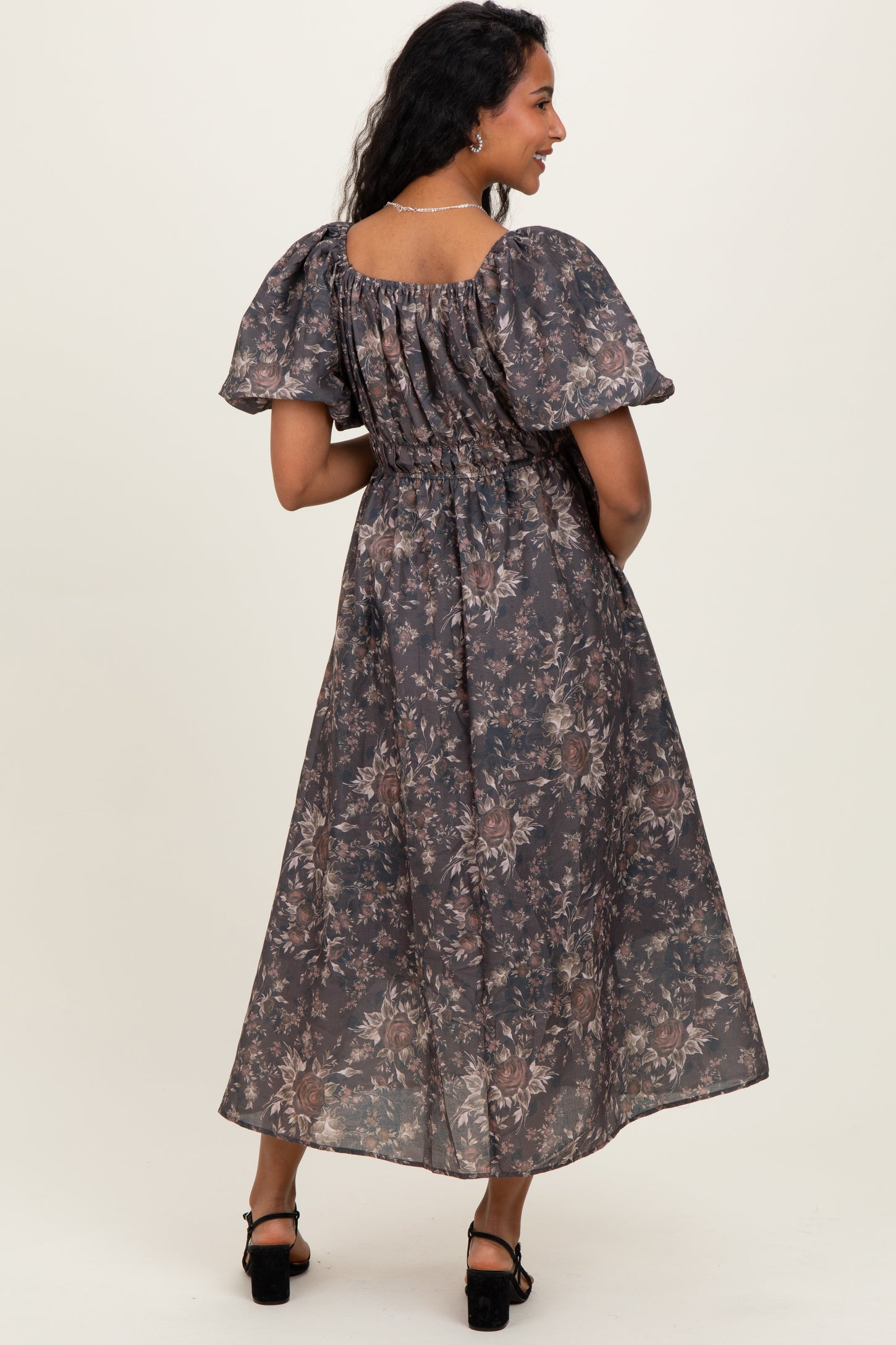 woman wearing a floral printed maternity maxi dress with puff sleeves and a smocked back, showcasing a baby bump