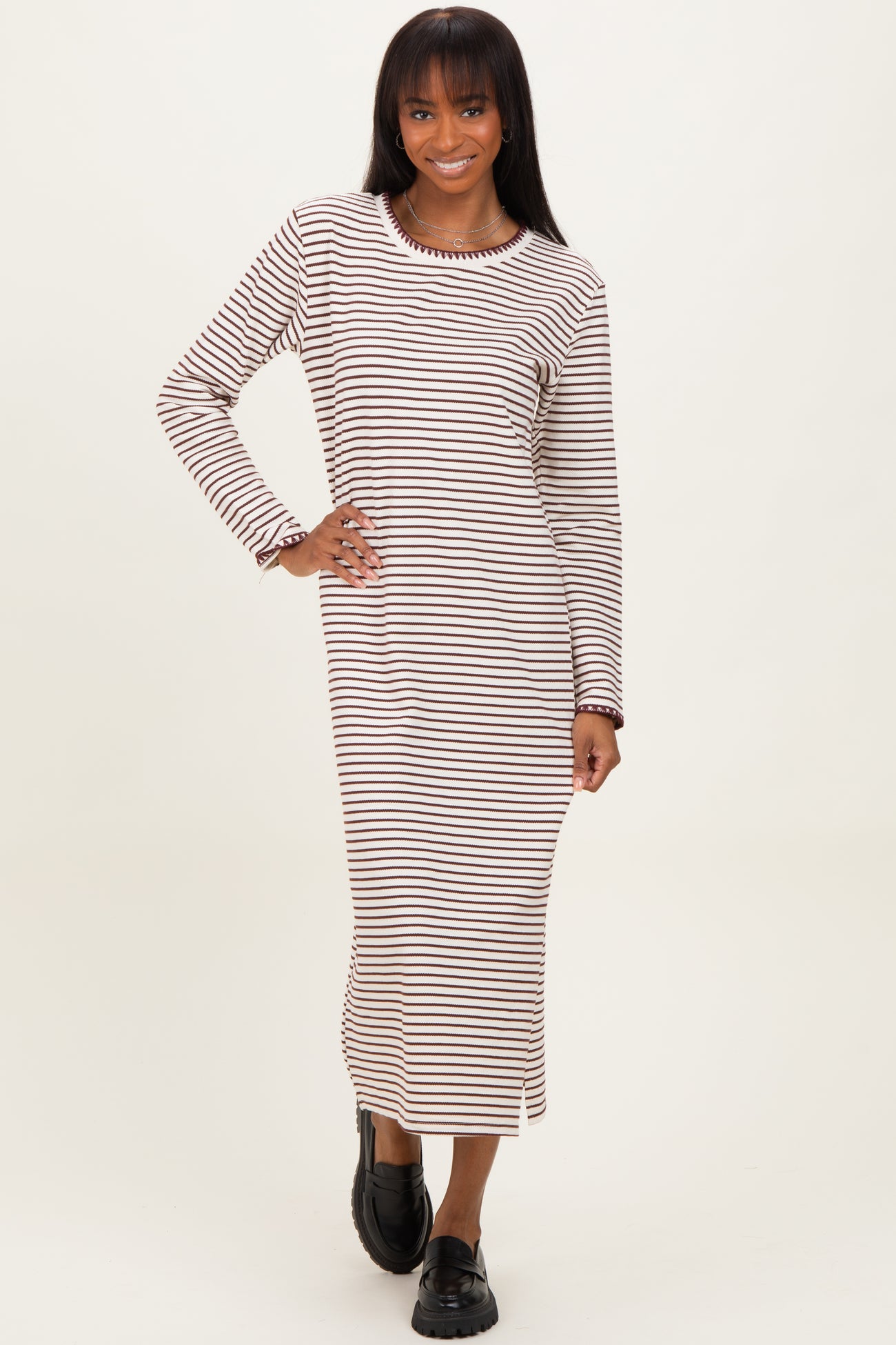 woman wearing a striped long sleeve midi dress in beige and brown with a relaxed fit and round neckline