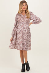 woman wearing a purple floral maternity dress with a smocked bodice and long sleeves, showing her baby bump