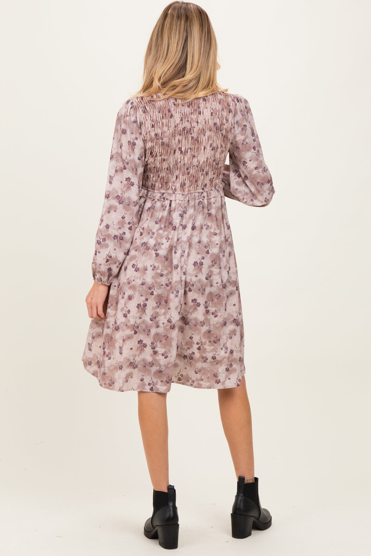 woman wearing a floral print maternity dress with smocked back detail and long sleeves, seen from the back