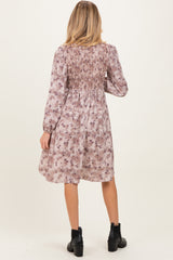 woman wearing a floral print maternity dress with smocked back detail and long sleeves, seen from the back