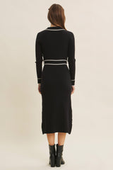 woman wearing a black ribbed midi dress with long sleeves and white accent details, shown from the back